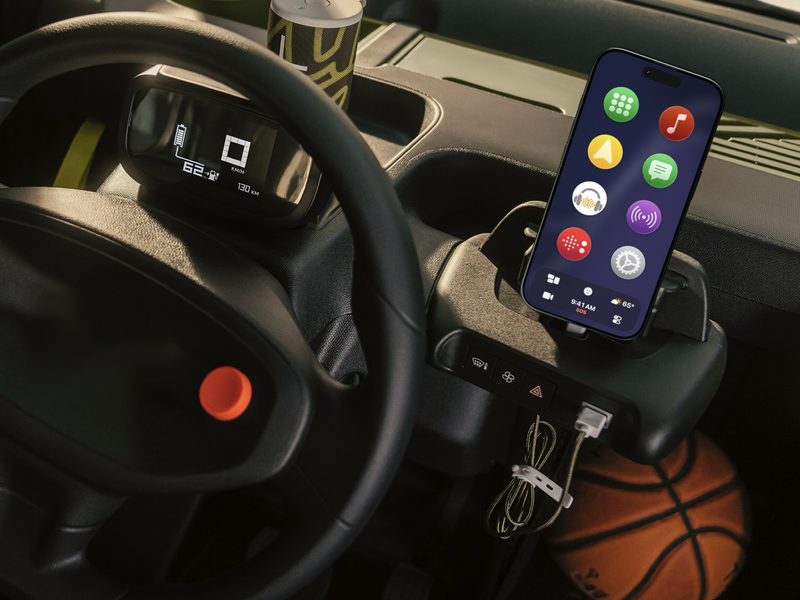 An iPhone running CarOS on its mount in a small license-free car